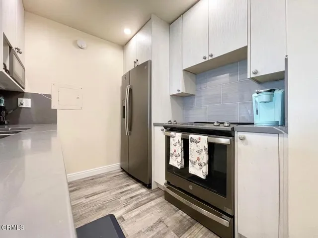 a kitchen with stainless steel appliances granite countertop a refrigerator a stove and a sink