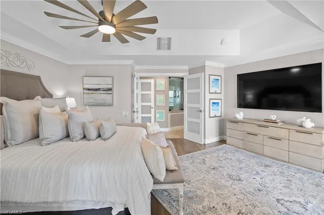 a bedroom with a bed a tv and wooden floor