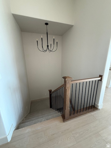 533 West S Temple Street, Unit 309 Tooele, UT 84074 - Photo 20 of 24 Staircase with wood finished floors and a chandelier
