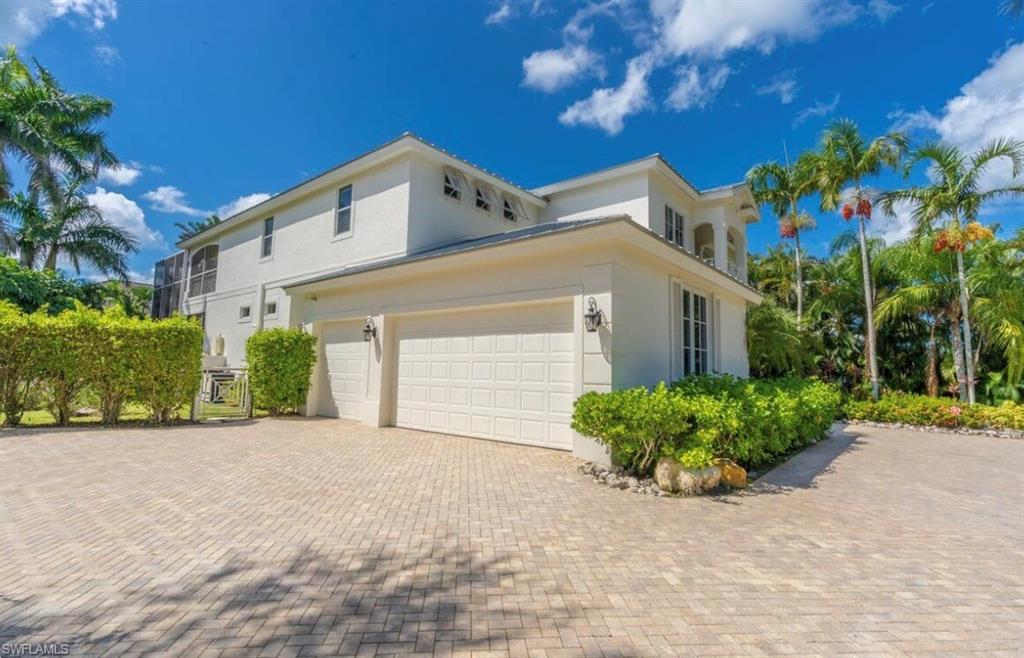 428 Rudder Road Naples, FL 34102 - Photo 3 of 49 View of side of home with stucco siding, decorative driveway, and an attached garage