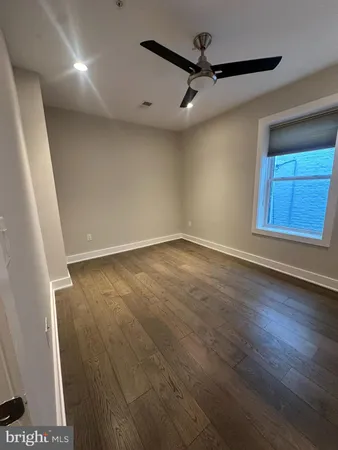 a view of an empty room with wooden floor and closet