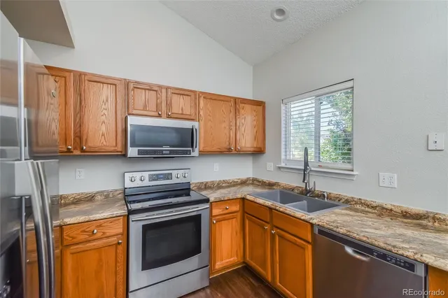 a kitchen with granite countertop a sink cabinets stainless steel appliances and a window