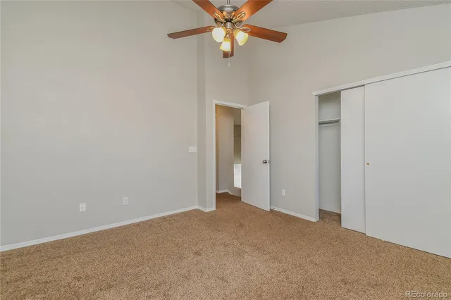 an empty room with closet and a chandelier fan