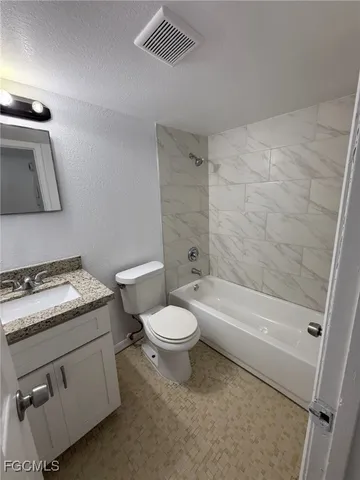 a bathroom with a granite countertop toilet a sink and bathtub