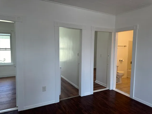 an empty room with wooden floor closet and windows