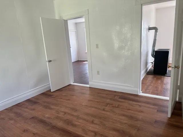 an empty room with wooden floor and mirror