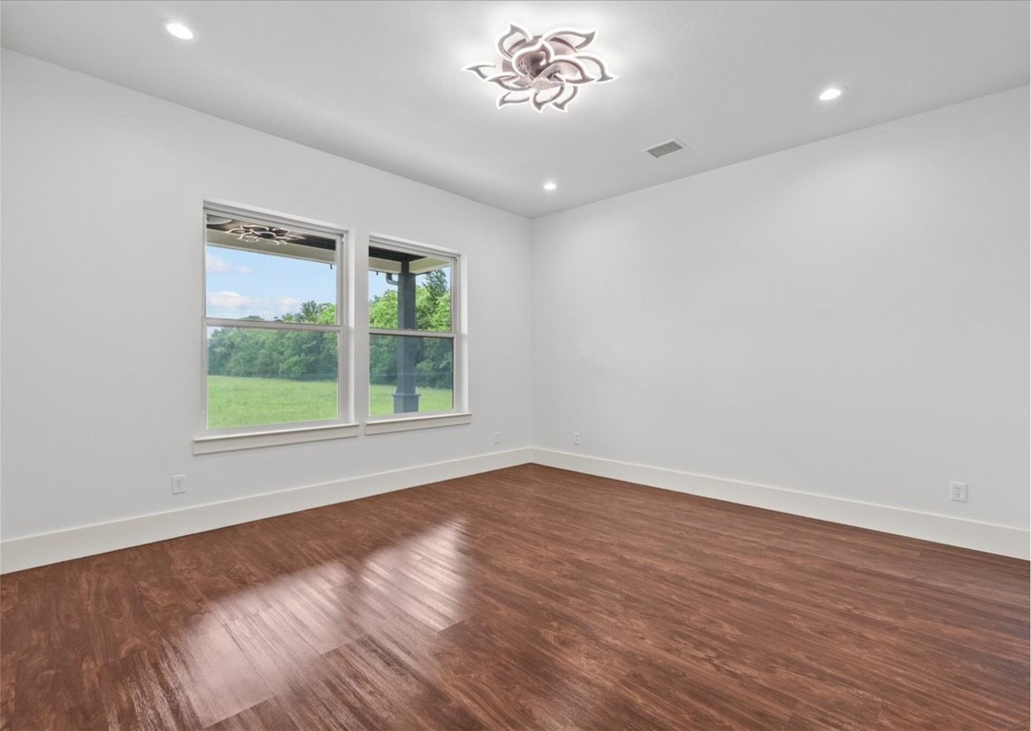 3237 Harkey Road Pearland, TX 77584 - Photo 18 of 46 Elegant primary suite featuring rich wood like flooring, designer lighting, oversized windows with peaceful property views, and a sophisticated contemporary design.