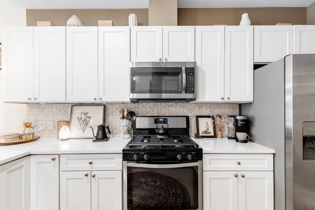 a kitchen with granite countertop white cabinets and stainless steel appliances