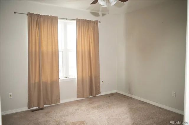 an empty room with windows and chandelier fan
