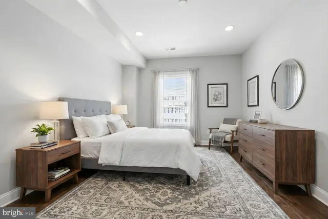 a bedroom with a bed a dresser with wooden floor