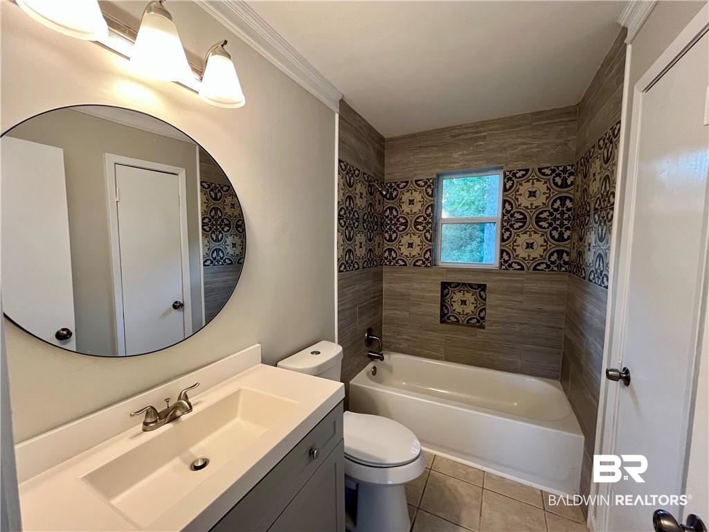 8636 Boe Road Irvington, AL 36544 - Photo 15 of 22 Bathroom with vanity, washtub / shower combination, light tile patterned floors, and crown molding