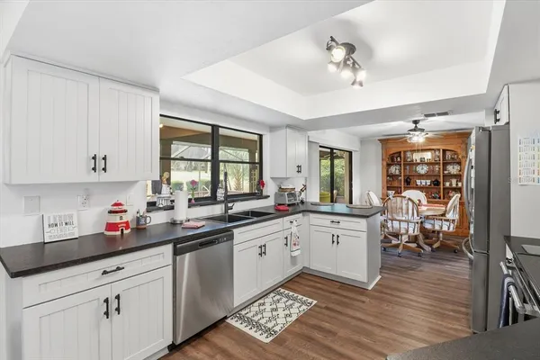 a kitchen with a sink dishwasher cabinets and dining table with wooden floor