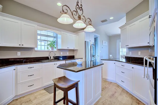 a kitchen with granite countertop a sink a stove and cabinets