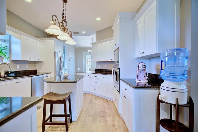 a kitchen with stainless steel appliances granite countertop a stove a sink dishwasher and a refrigerator with wooden floor