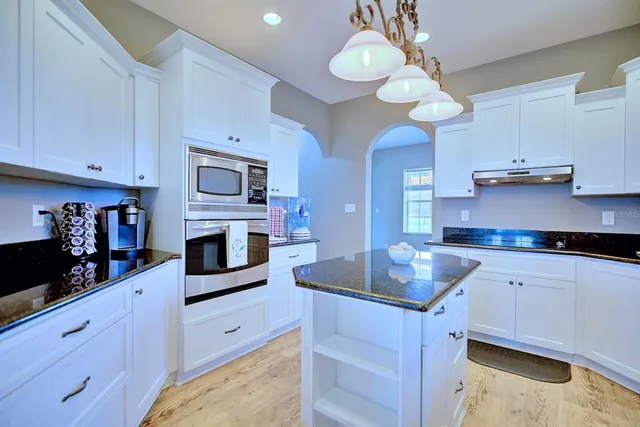 a kitchen with granite countertop a sink a stove and cabinets