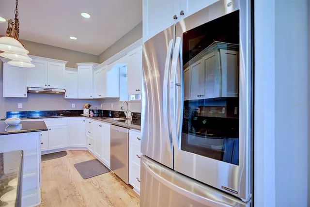 a kitchen with granite countertop white cabinets stainless steel appliances and sink