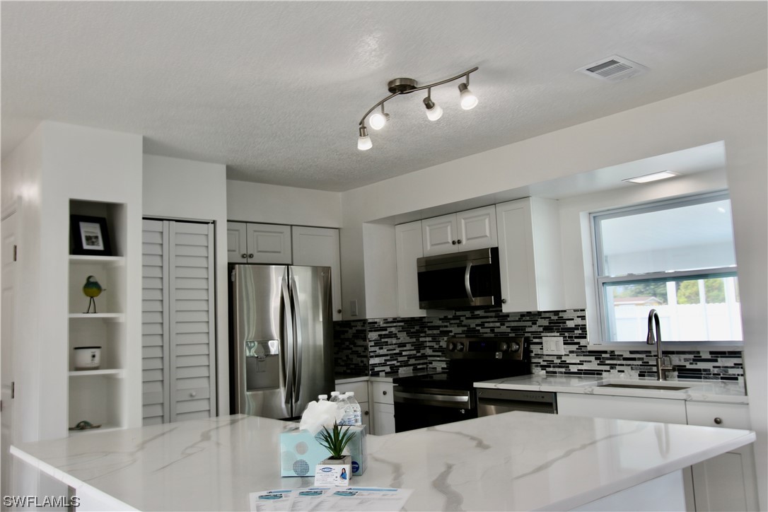 116 Oleander Road Lehigh Acres, FL 33936 - Photo 8 of 31 a kitchen with stainless steel appliances a refrigerator sink and microwave