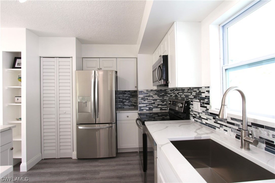 116 Oleander Road Lehigh Acres, FL 33936 - Photo 10 of 31 a kitchen with a refrigerator sink and white cabinets