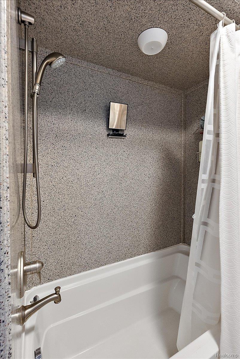 60718 Campground Road Washington, MI 48094 - Photo 28 of 37 White bathtub with brushed nickel fixtures and a textured shower surround