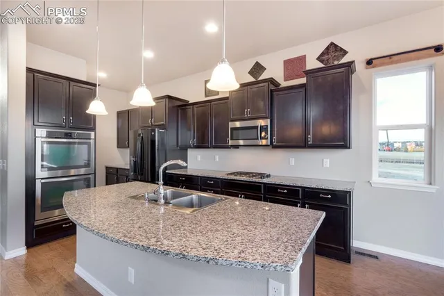 a kitchen with stainless steel appliances granite countertop a sink a stove and a refrigerator