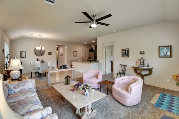 a living room with furniture kitchen view and a wooden floor