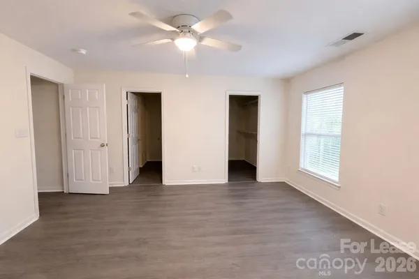 an empty room with chandelier fan and windows
