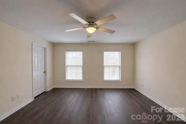 a view of an empty room with window and wooden floor