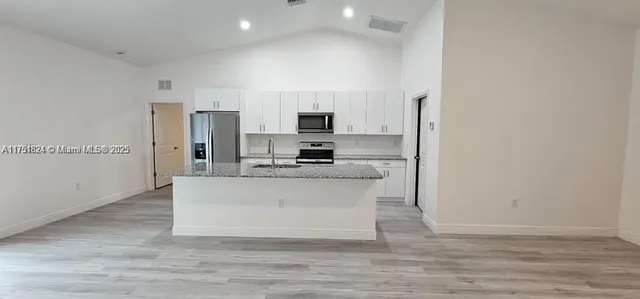 a view of kitchen with stainless steel appliances wooden floor and chair