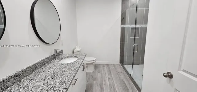 a bathroom with a granite countertop sink a toilet and a mirror