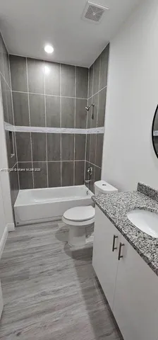a bathroom with a granite countertop bathtub sink vanity mirror and toilet