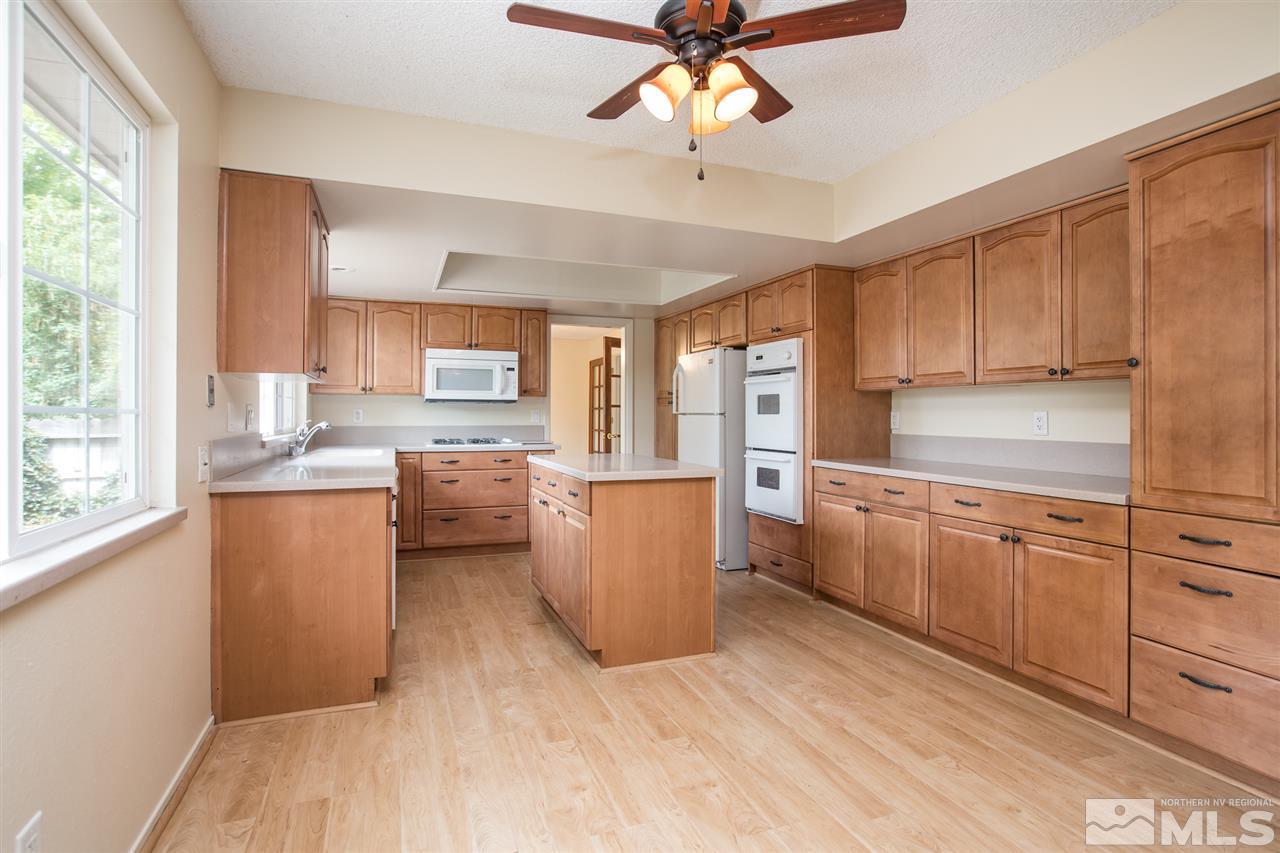 885 Twin Pines Road Reno, NV 89509 - Photo 7 of 25 a kitchen with a refrigerator a stove top oven a sink dishwasher and white cabinets with wooden floor