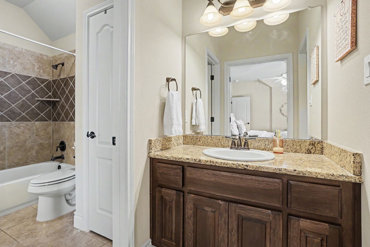 809 Prairie Dunes Drive Georgetown, TX 78628 - Photo 30 of 40 Granite counters and a warm wood vanity elevate this inviting bathroom space.