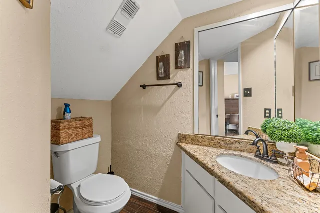 a bathroom with a granite countertop toilet sink and mirror