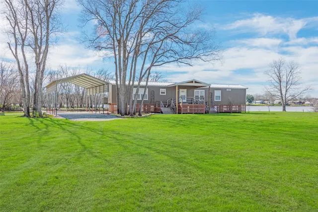 a large tree in front of a house with a garden