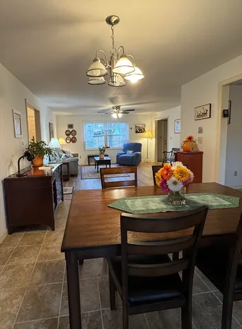 a dining room with wooden floor a chandelier a wooden table and chairs