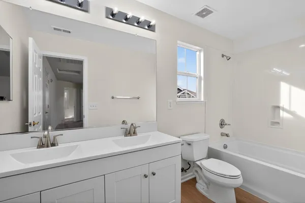 a bathroom with a double vanity sink toilet mirror and bathtub
