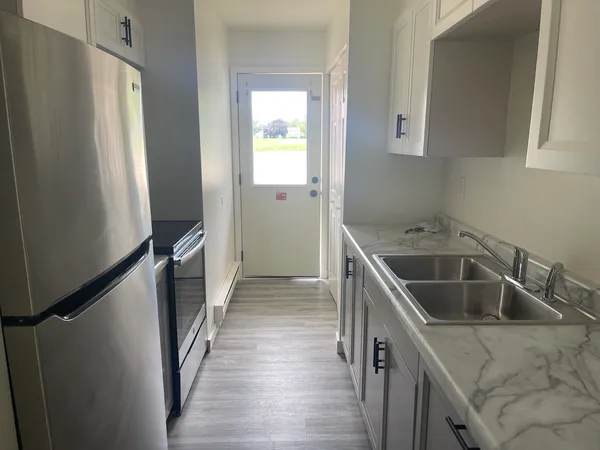 a kitchen with a sink a refrigerator and cabinets