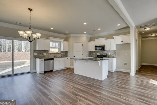 a kitchen with stainless steel appliances kitchen island granite countertop a stove a sink dishwasher a refrigerator and white cabinets with wooden floor