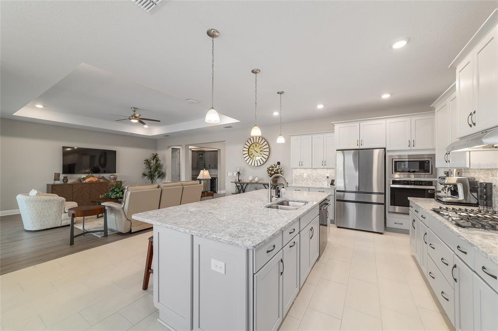 9681 Southwest 82nd Street Road Ocala, FL 34481 - Photo 15 of 62 a large kitchen with stainless steel appliances kitchen island granite countertop a large center island a stove a sink a dining table and chairs