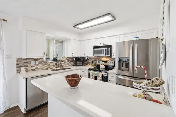 a kitchen with appliances a stove a sink dishwasher a refrigerator and cabinets with wooden floor