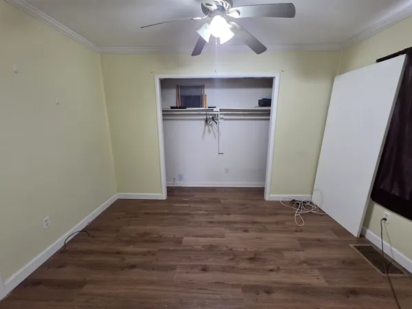 a view of an empty room with wooden floor and a window
