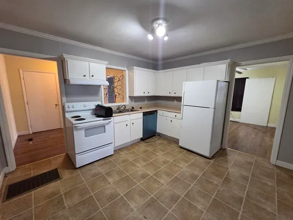 a kitchen with a stove a refrigerator and white cabinets