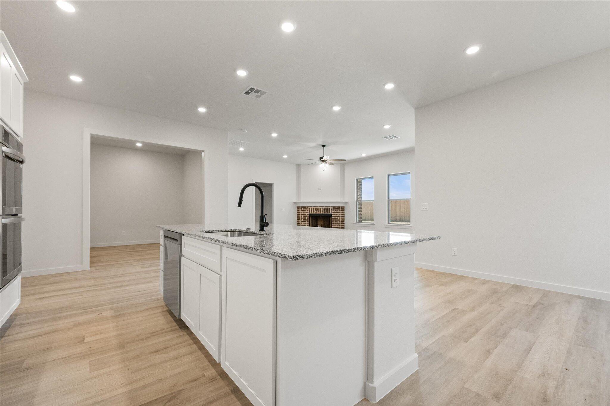 6101 121st Street Lubbock, TX 79424 - Photo 12 of 29 a large white kitchen with wooden floor and a sink