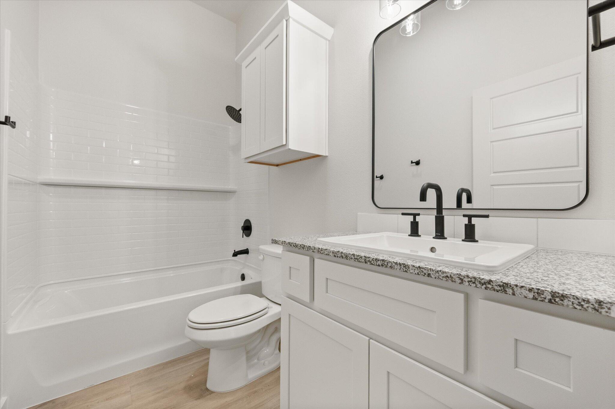 6101 121st Street Lubbock, TX 79424 - Photo 25 of 29 a bathroom with a granite countertop toilet a sink and a bathtub