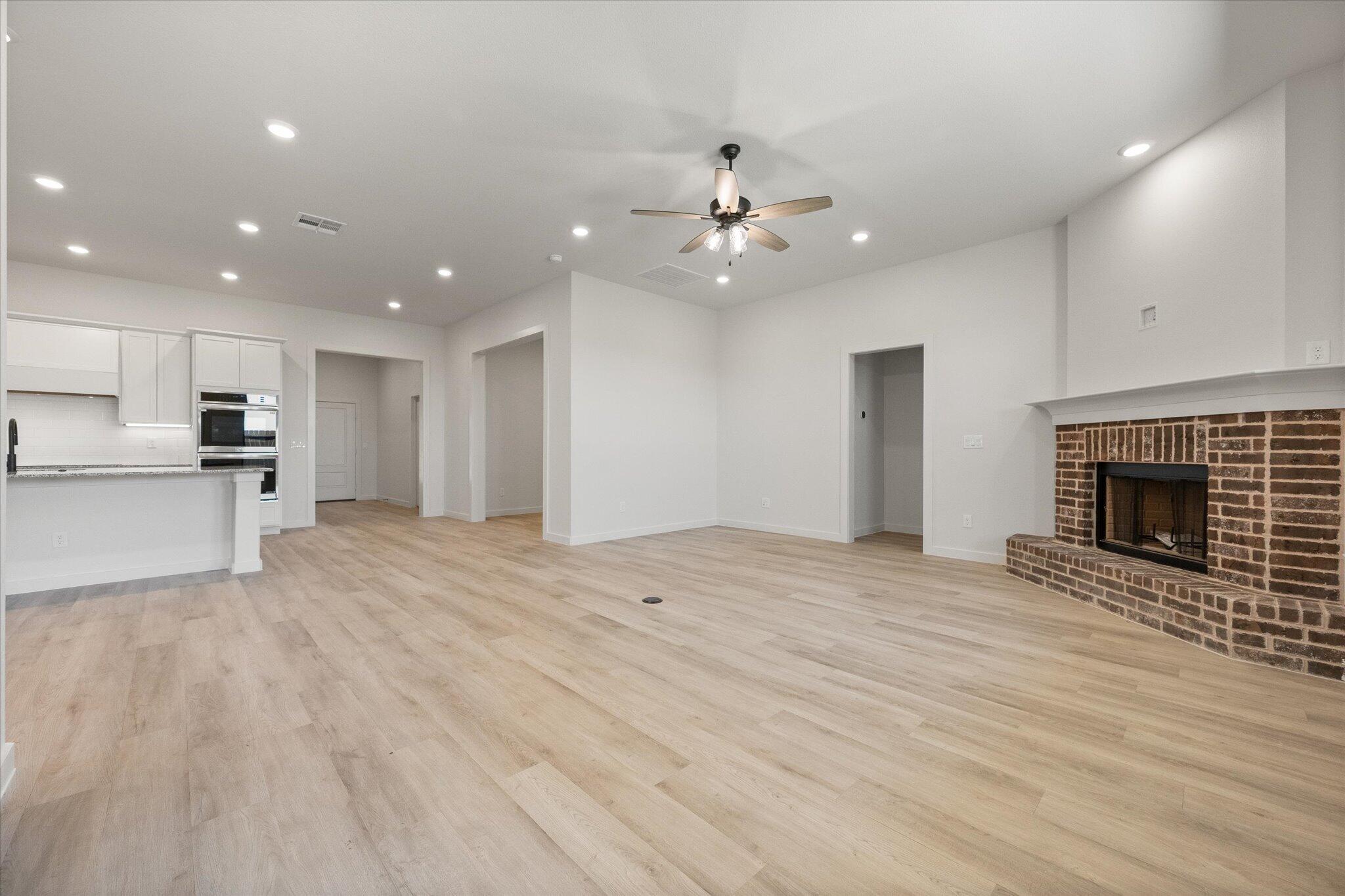 6101 121st Street Lubbock, TX 79424 - Photo 6 of 29 an empty room with wooden floor fireplace and kitchen view