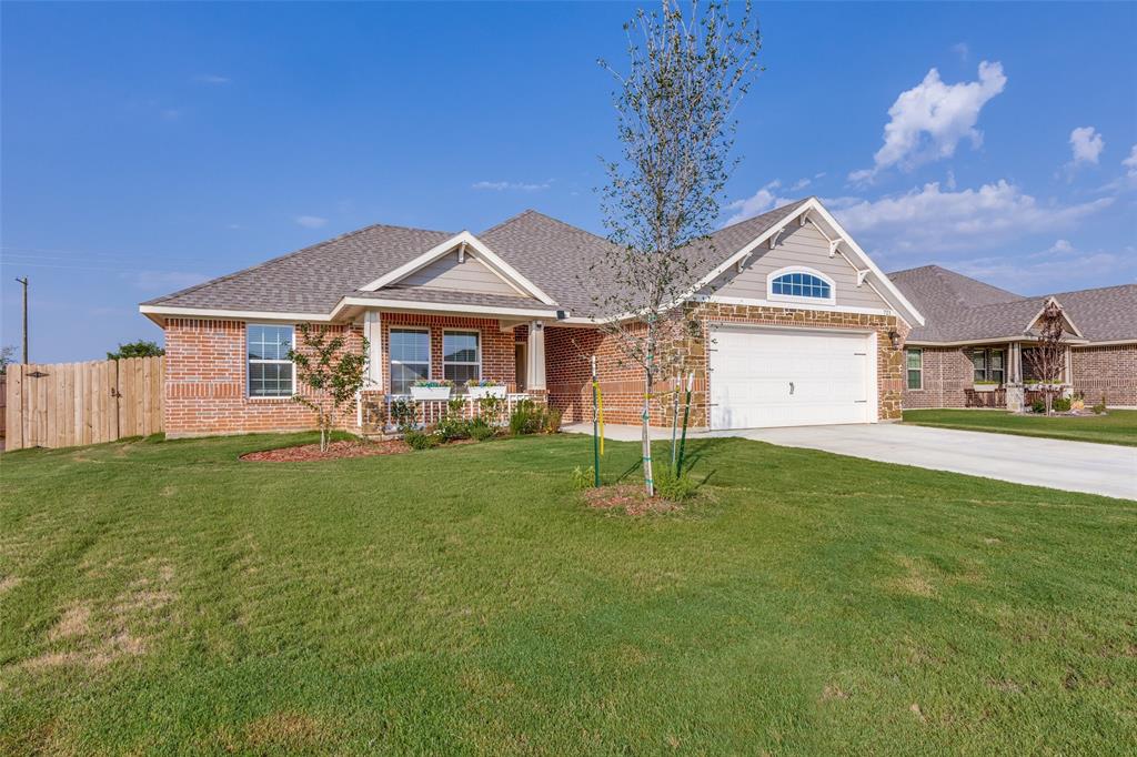 View of front facade with concrete driveway, brick siding, a shingled roof, and covered porch