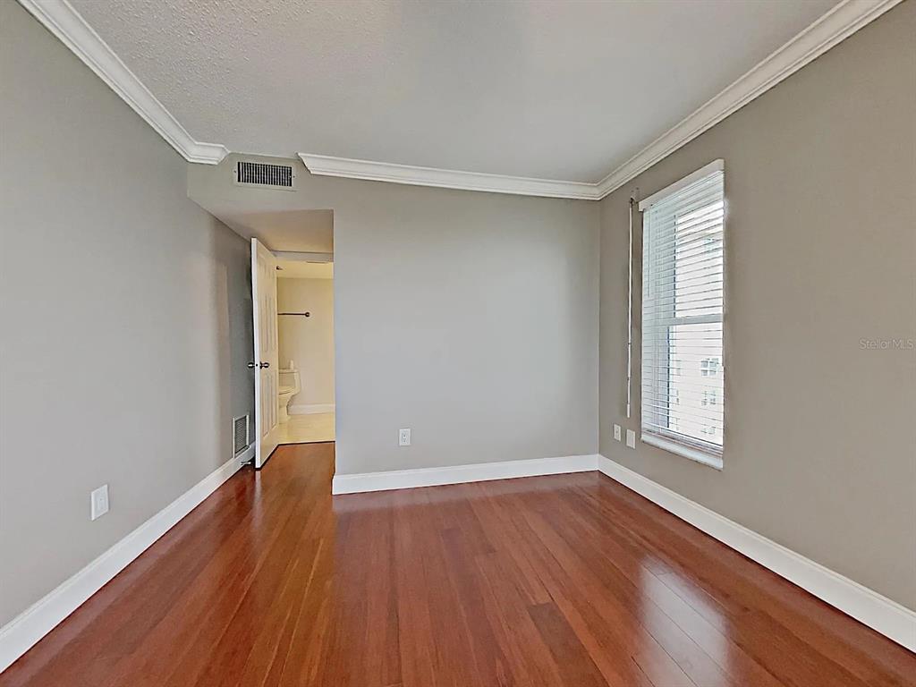 5220 Brittany Drive South, Unit 1502 St. Petersburg, FL 33715 - Photo 15 of 21 a view of an empty room with wooden floor and a window