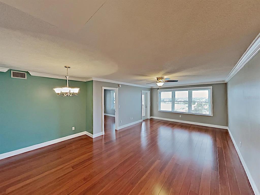 5220 Brittany Drive South, Unit 1502 St. Petersburg, FL 33715 - Photo 9 of 21 a view of an empty room with wooden floor and a window