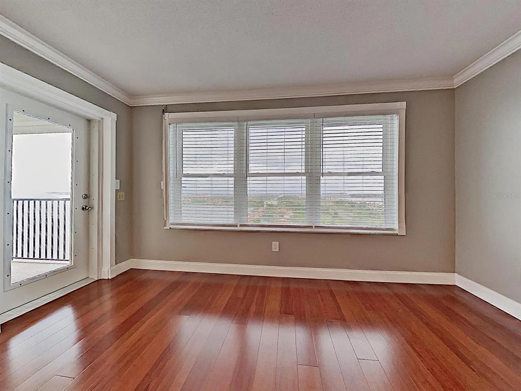 5220 Brittany Drive South, Unit 1502 St. Petersburg, FL 33715 - Photo 10 of 21 a view of an empty room with wooden floor and a window
