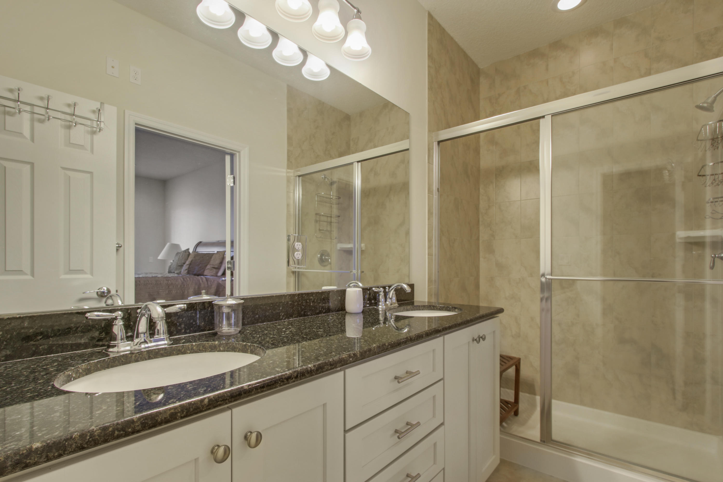 1168 South Community Drive Jupiter, FL 33458 - Photo 10 of 18 a bathroom with a granite countertop sink a mirror and a shower